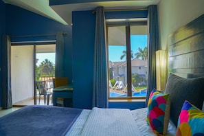 A hotel room with a bed, a desk, and a view of a swimming pool.