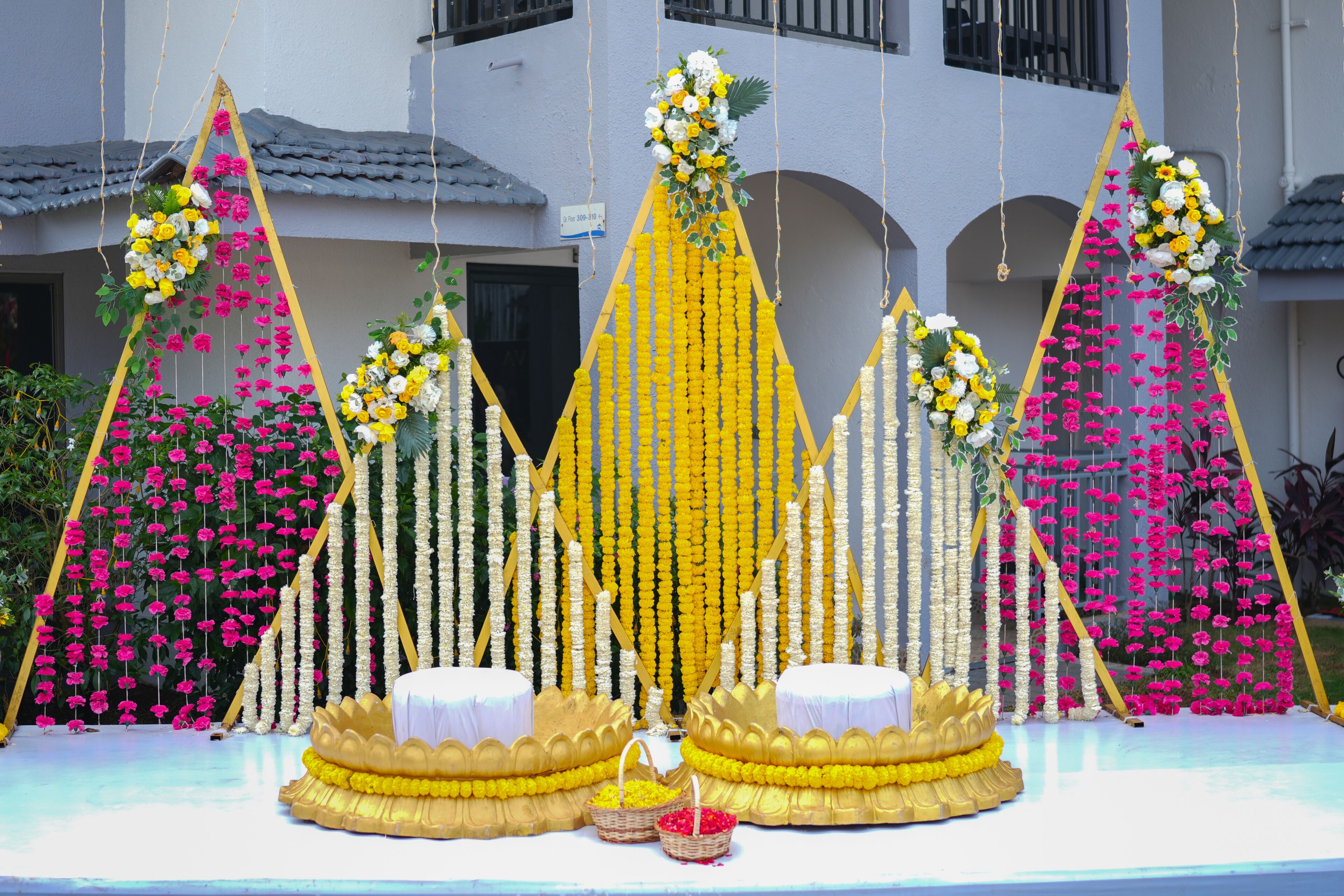 Un escenario con arreglos florales y estructuras doradas.