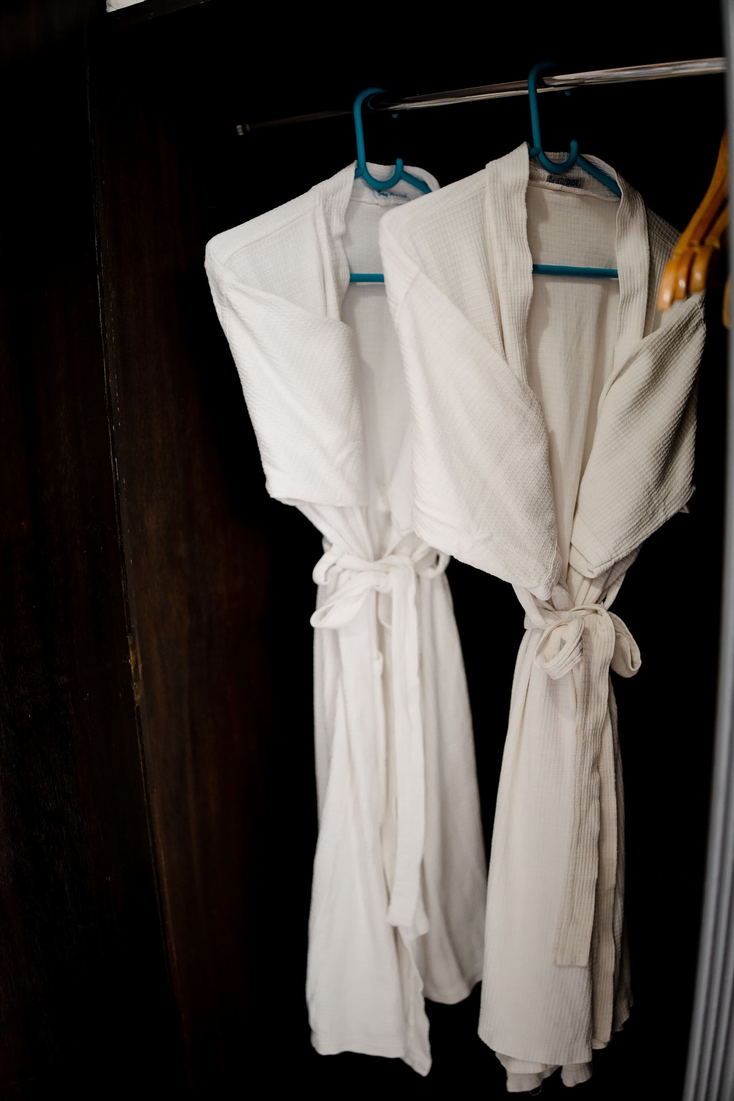 Two white robes hanging on a rack.