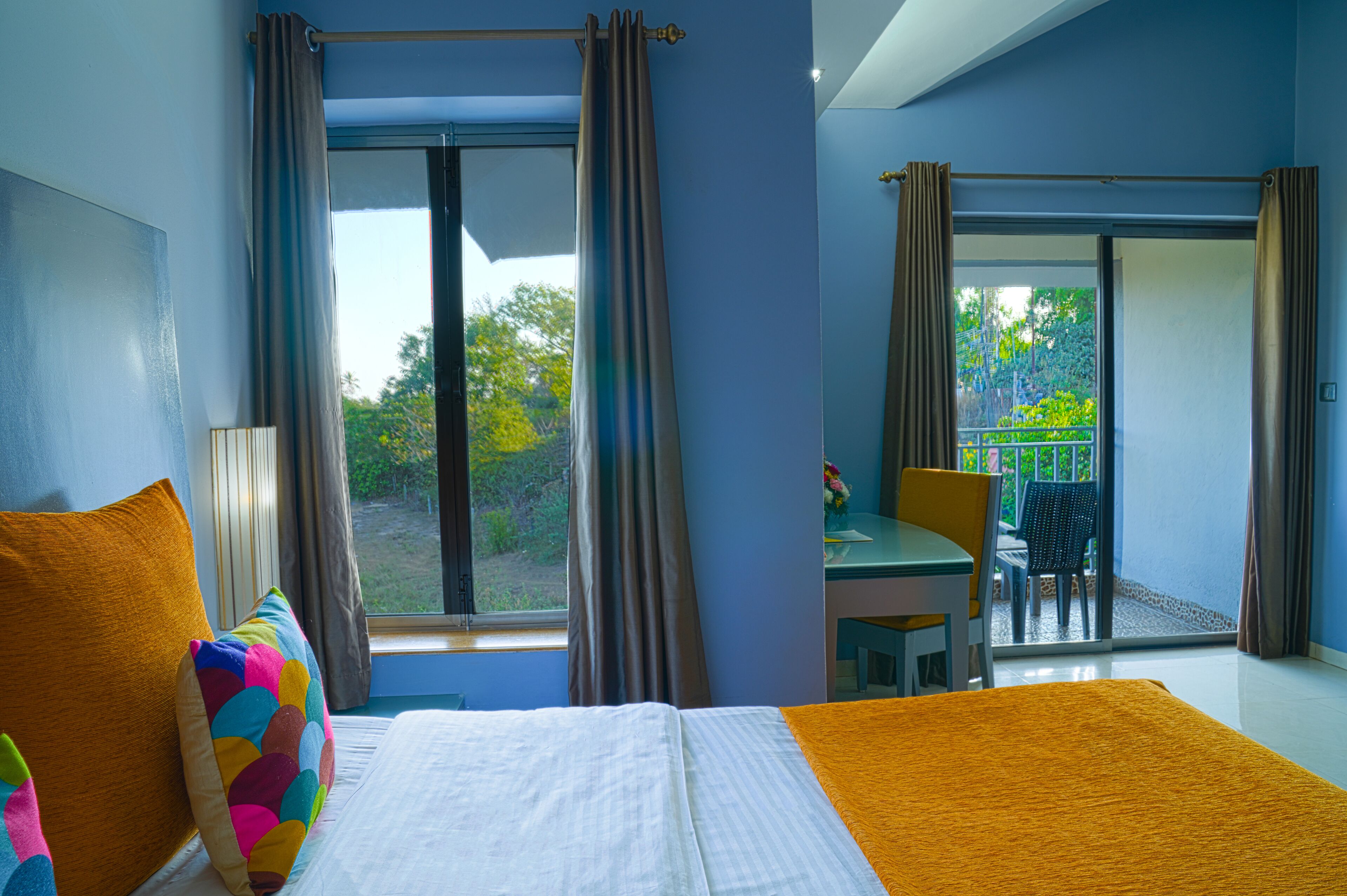 A hotel room with a bed, a desk, and a view of the outdoors.