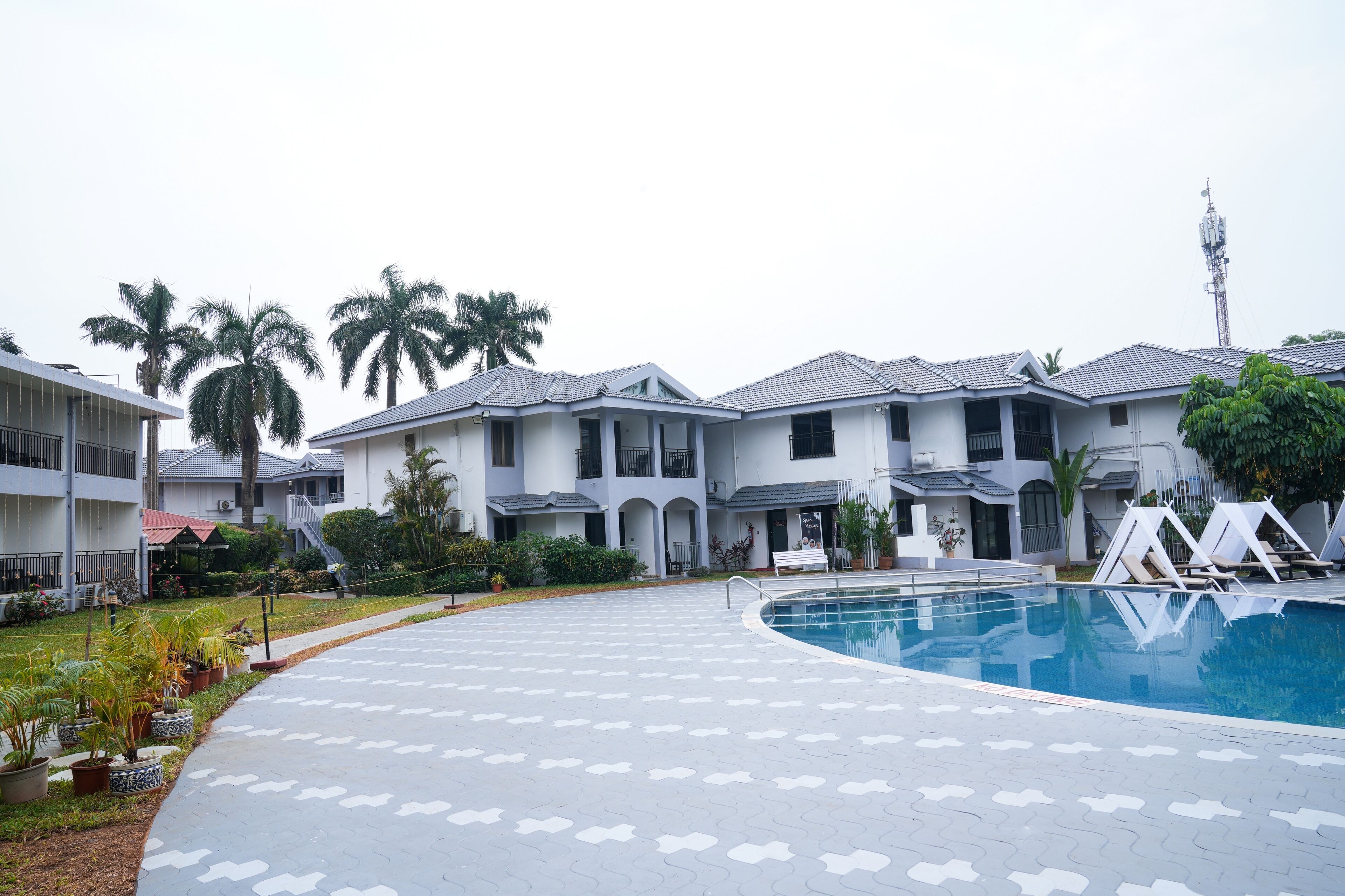 Zona residencial com piscina, palmeiras e uma casa de vários andares com telhado em cerâmica.