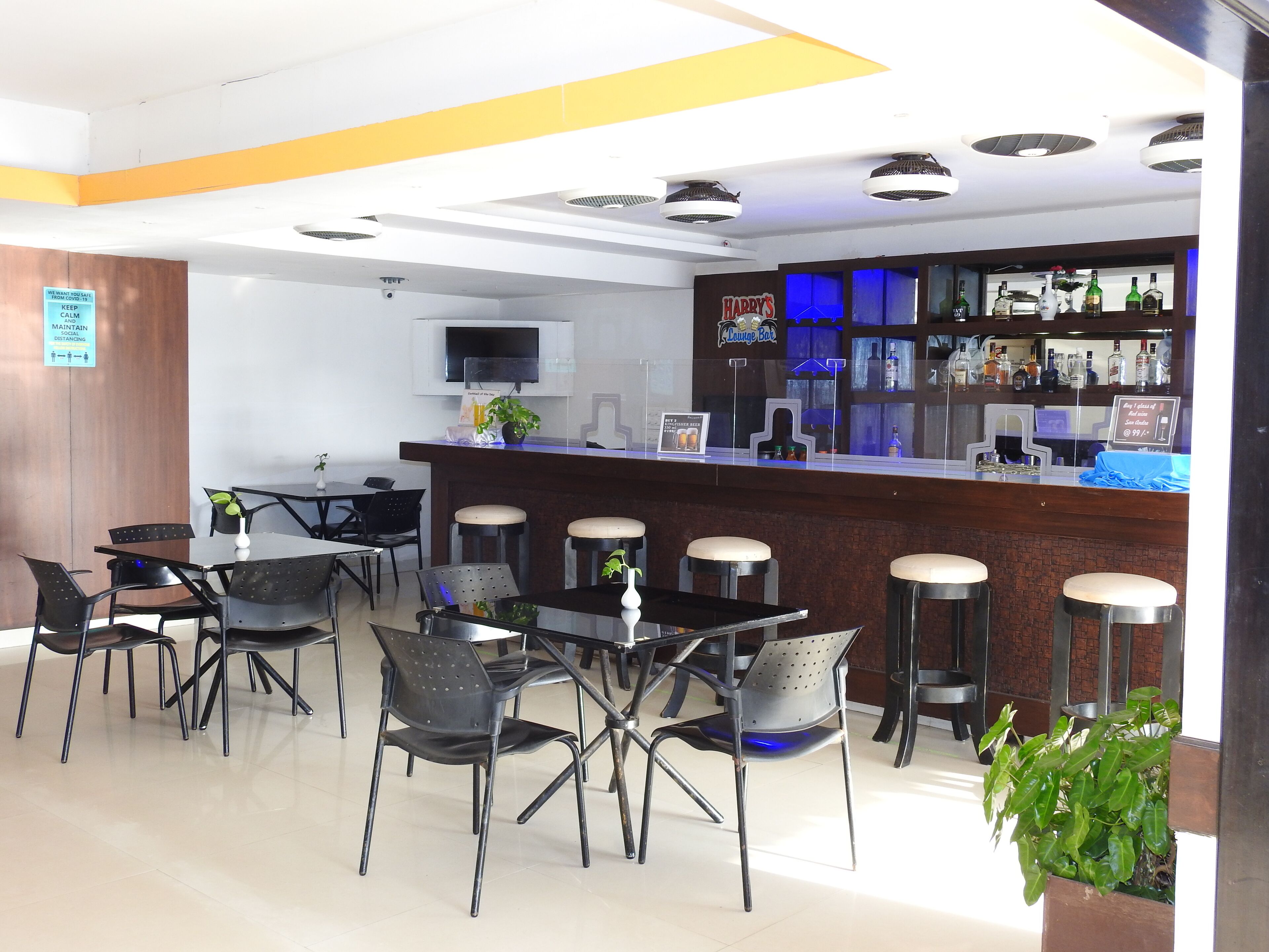 Zona de bar con taburetes, una barra y una pantalla de televisión.