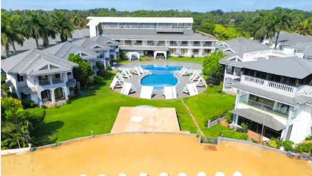 A resort with a central pool, multiple guest buildings, and a sandy area with round seating. - Regenta Baywatch Resort Goa (Colva)