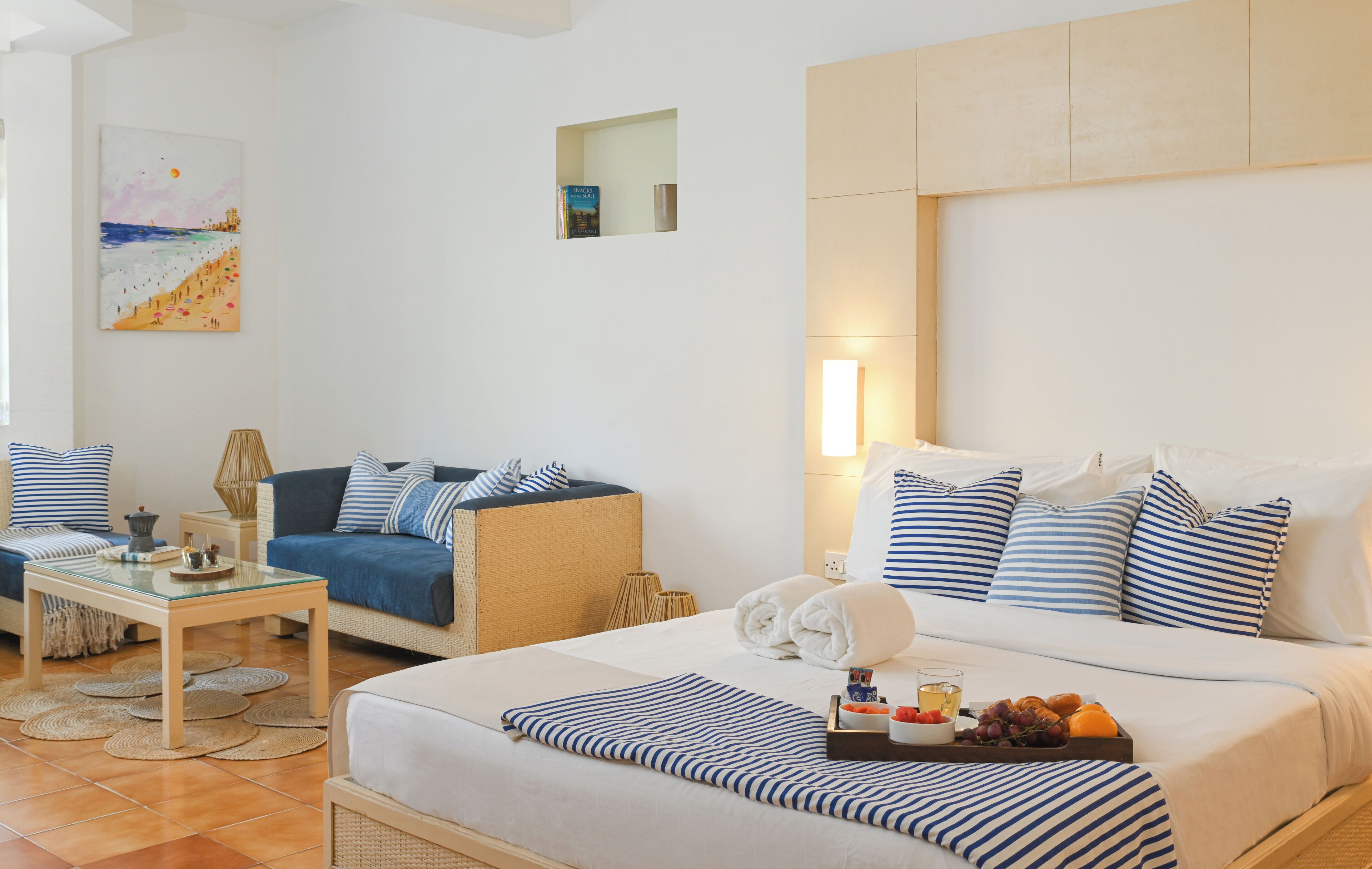 Quarto de hotel com cama, sofá, mesa pequena e um quadro na parede.