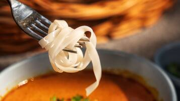 A bowl of soup with noodles being lifted by a fork.