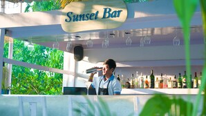 Un bar llamado "Sunset Bar" con un cantinero preparando una bebida.