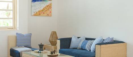 A living room with a sofa, a coffee table, and a painting of a beach scene.