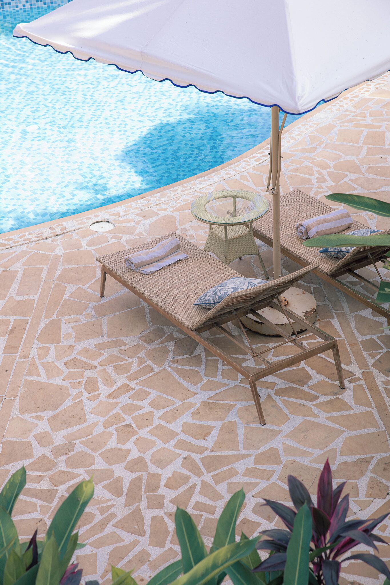 A poolside area with lounge chairs, a table, and an umbrella.