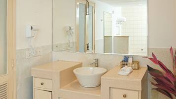 A bathroom with a white sink, two towel racks, a mirror, and a hairdryer on the wall.