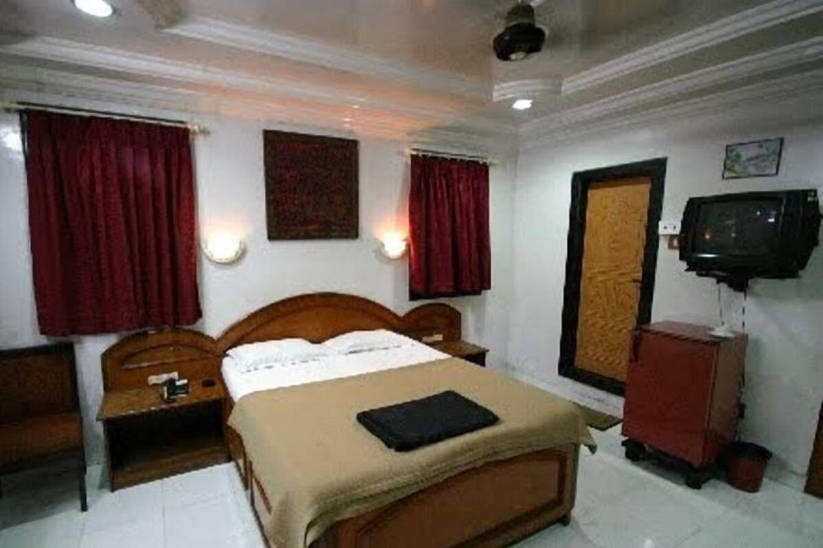 A hotel room with a bed, a TV, a desk, and a chair.