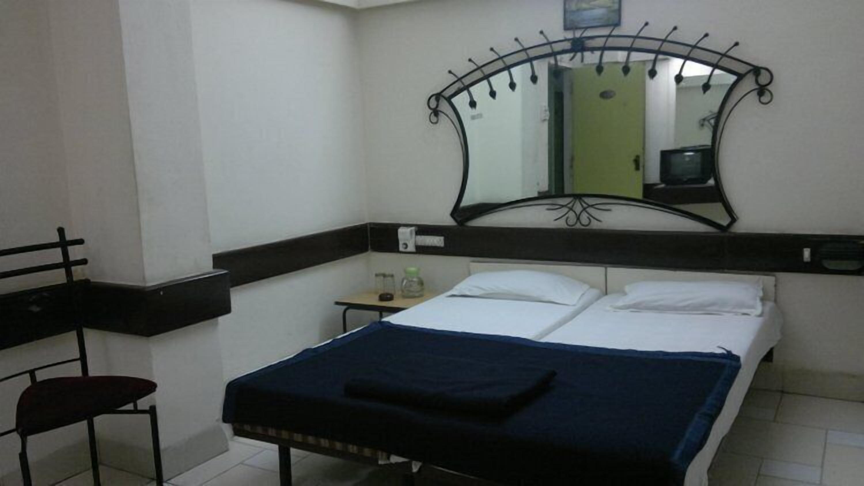 Ein Hotelzimmer mit Bett, Schreibtisch, Stuhl und Spiegel.