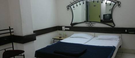 Ein Hotelzimmer mit Bett, Schreibtisch, Stuhl und Spiegel.