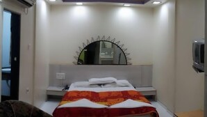 A bedroom with a bed, a mirror, a ceiling fan, and an air conditioning unit. - Hotel Sea Lord (Mumbai)