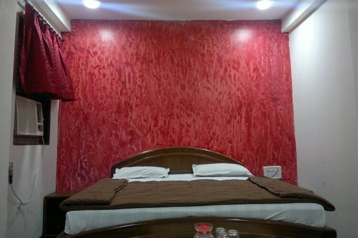 A room with a bed, red textured walls, and a ceiling light fixture.