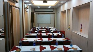 A conference room with rows of tables, each with water bottles and red napkins. - Hotel Sea Lord (Mumbai)