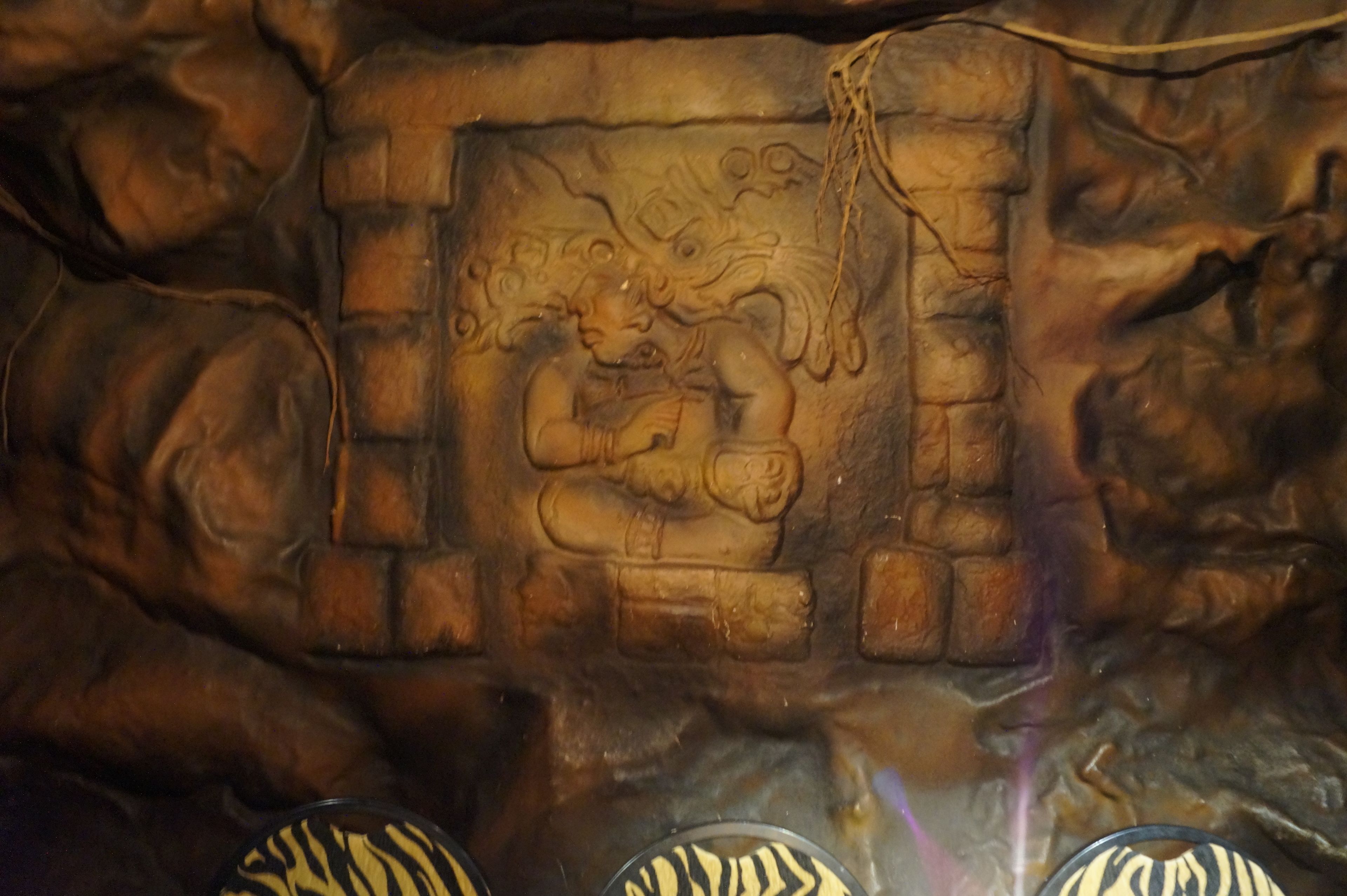 A stone wall with a carved figure and a rope.