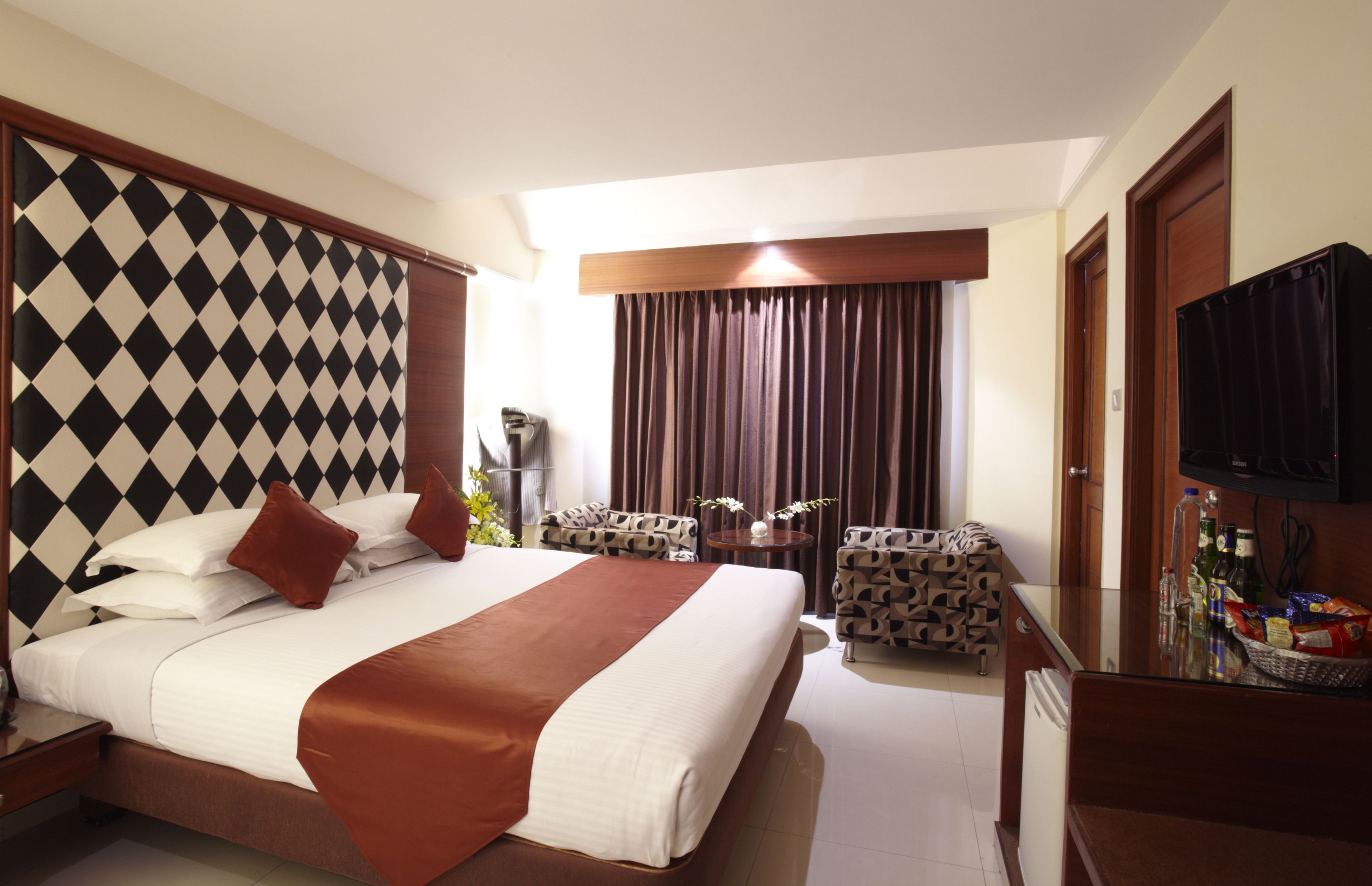 A hotel room with a large bed, a TV, a desk, and a chair.