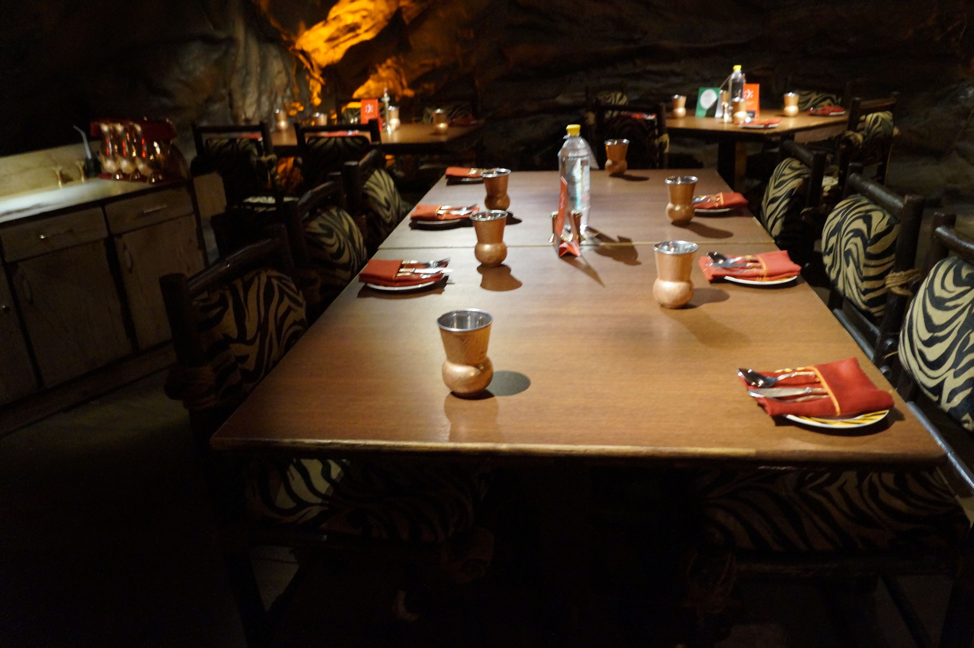 A long dining table set with plates, cutlery, and a bottle of water.