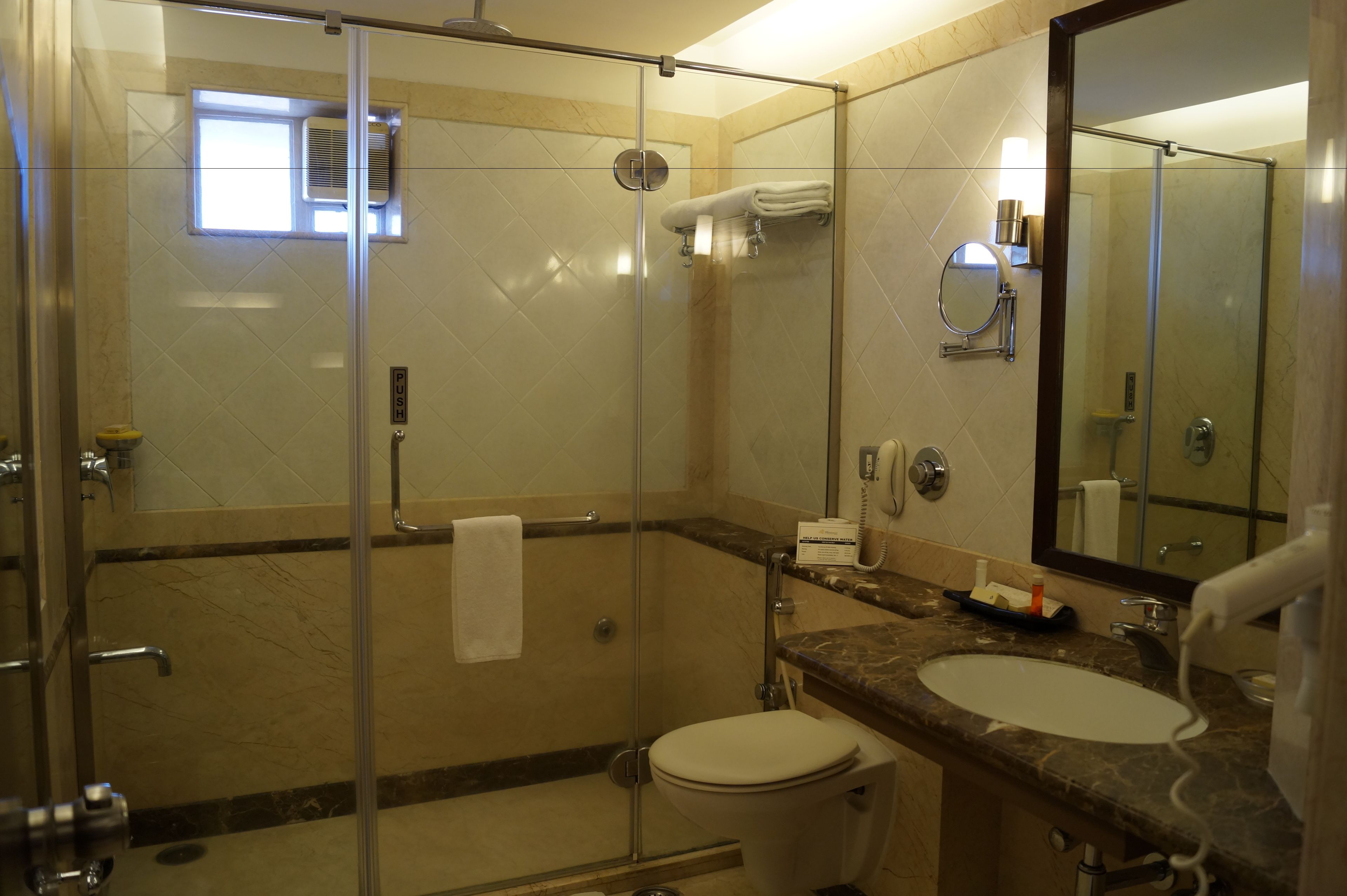A modern bathroom with a glass-enclosed shower, a marble sink, and a large mirror.