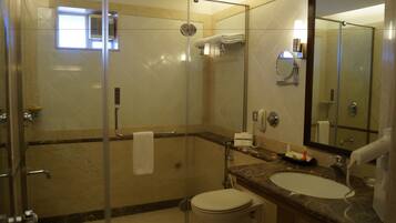 Een moderne badkamer met een douche met glazen wanden, een marmeren wastafel en een grote spiegel.