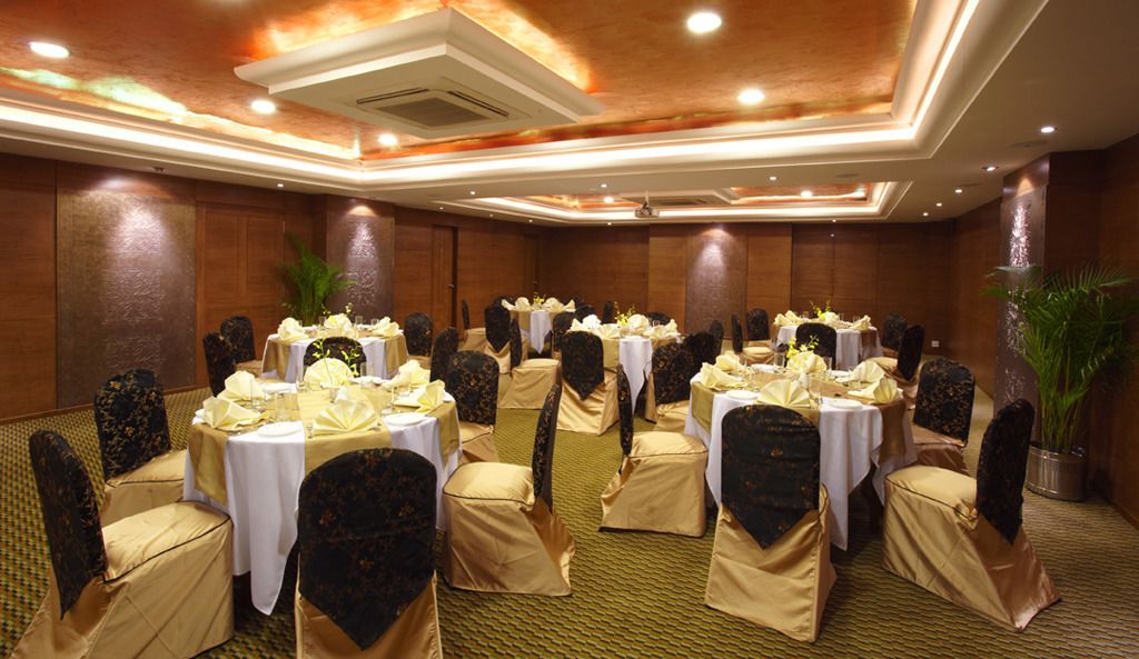 A banquet hall with round tables, chairs, and a carpeted floor.