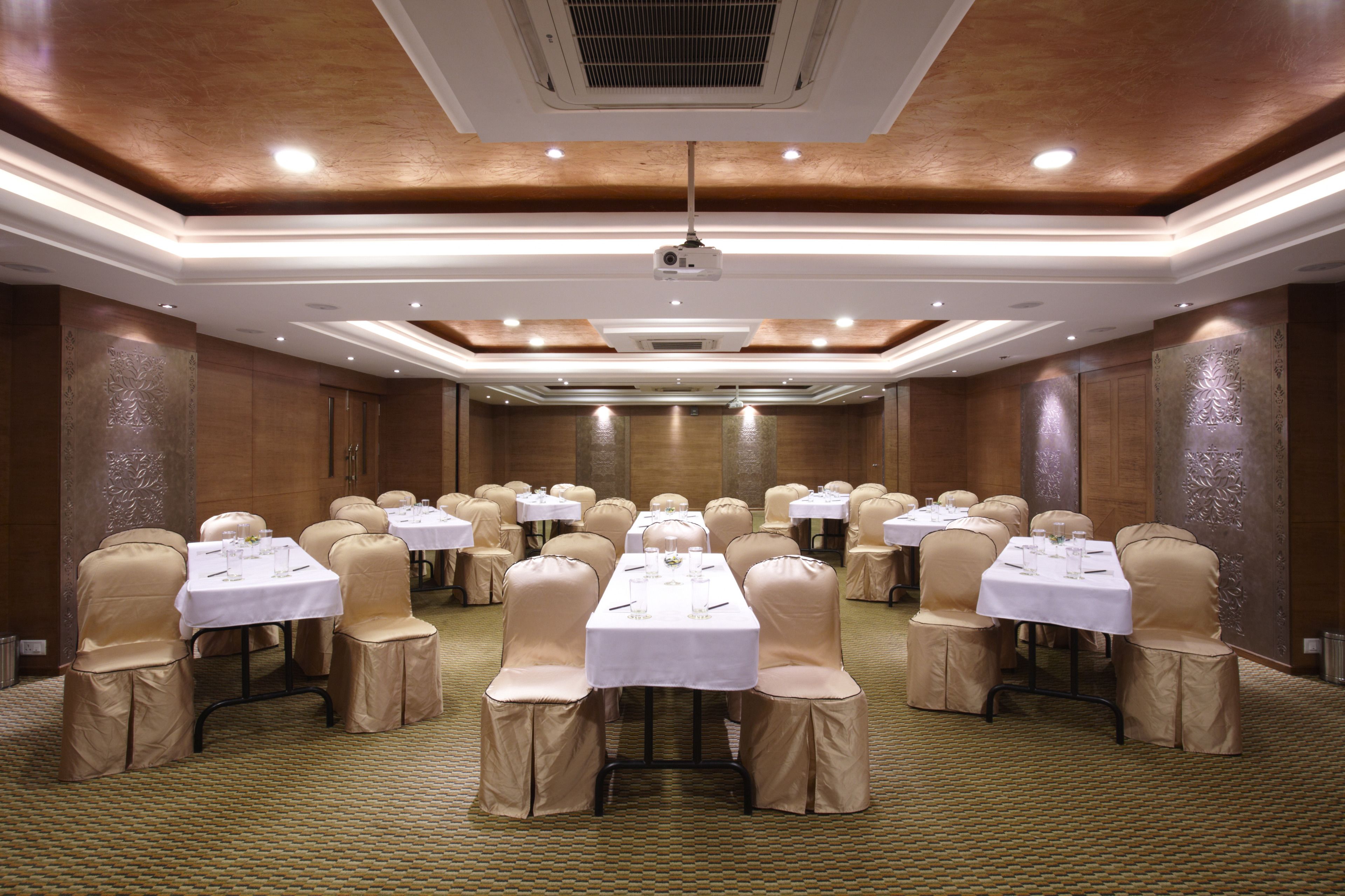 Une salle de conférence dotée de plusieurs tables et de chaises, et équipée de tables, de chaises et d’un projecteur.