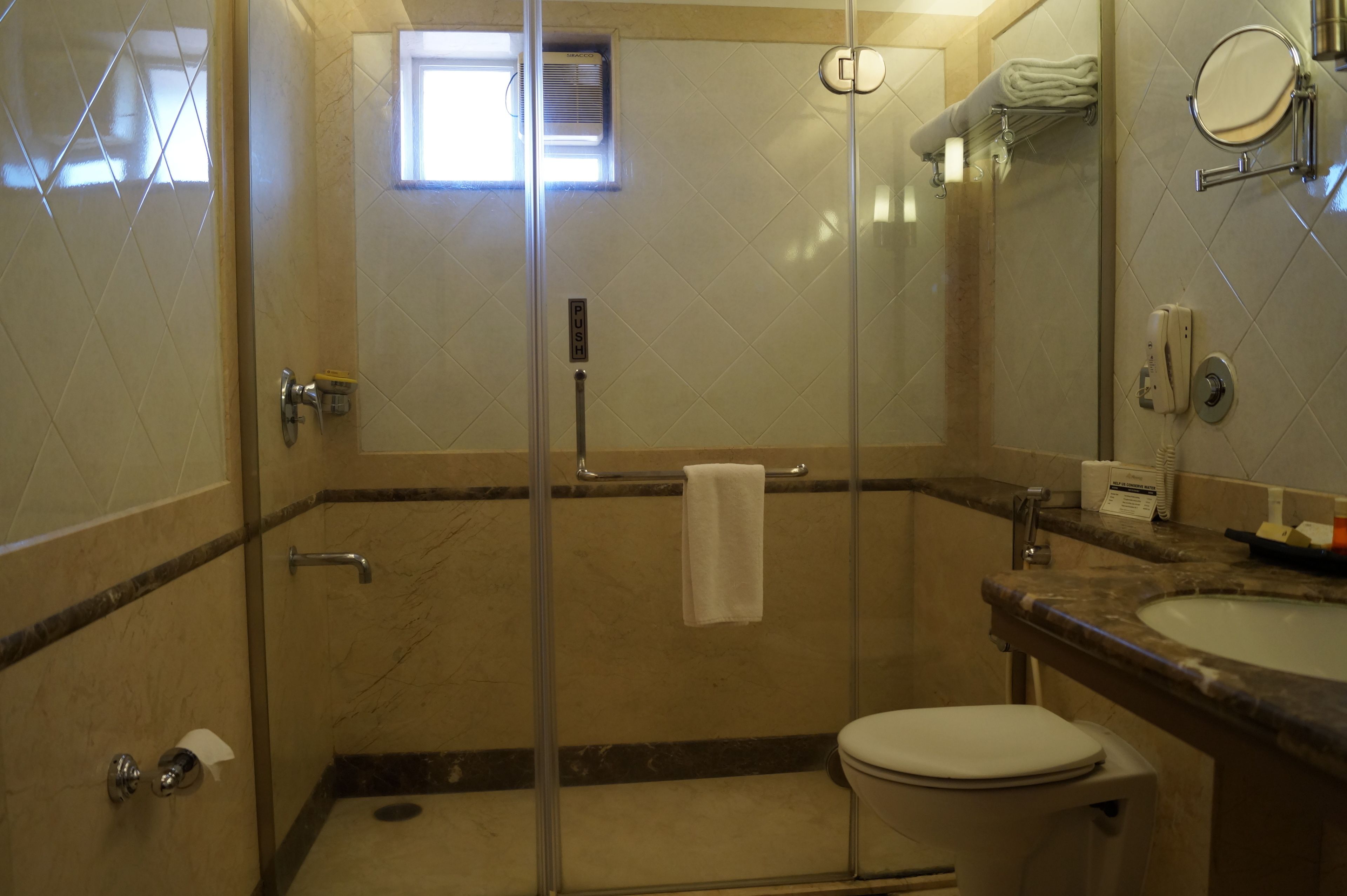 Un baño con ducha de vidrio, inodoro, lavamanos y espejo.