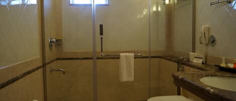 Un baño con ducha de vidrio, inodoro, lavamanos y espejo.