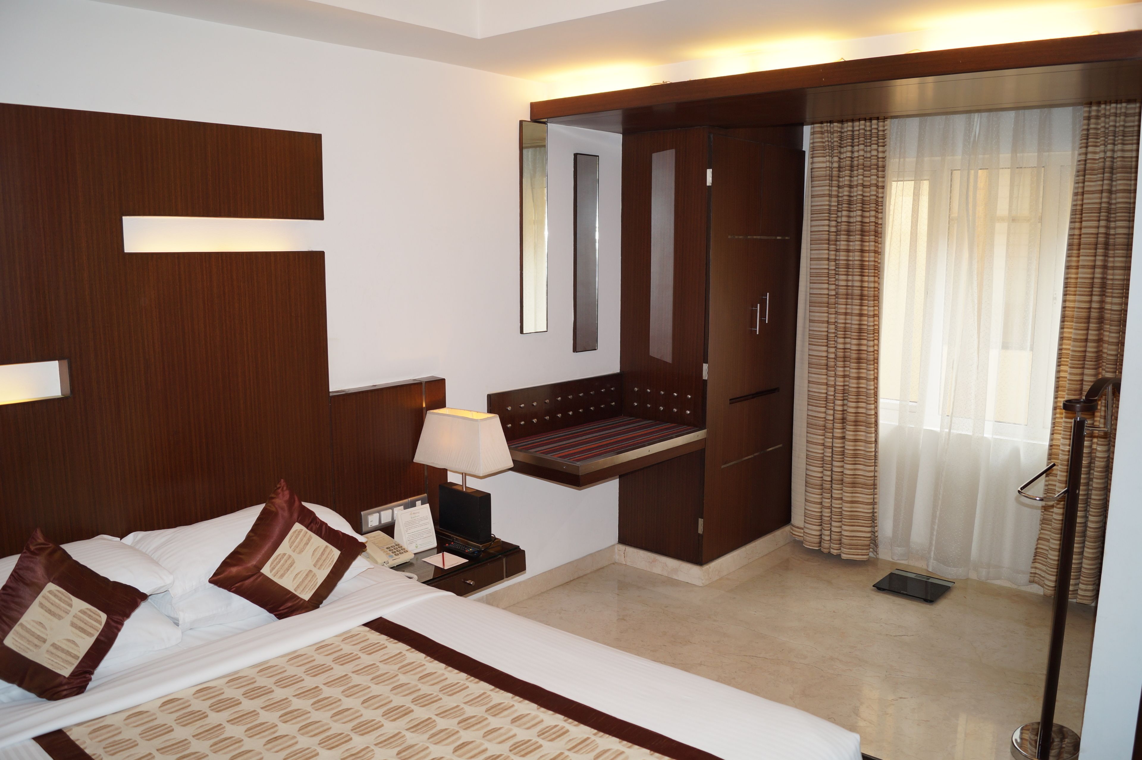 Una habitación de hotel con cama, mesita de noche, lámpara y espejo.