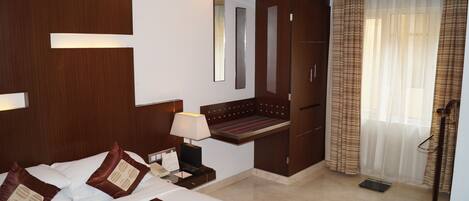 Una habitación de hotel con cama, mesita de noche, lámpara y espejo.