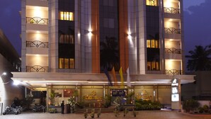 Un hotel con un ingresso imponente, numerosi balconi e una facciata ben illuminata.