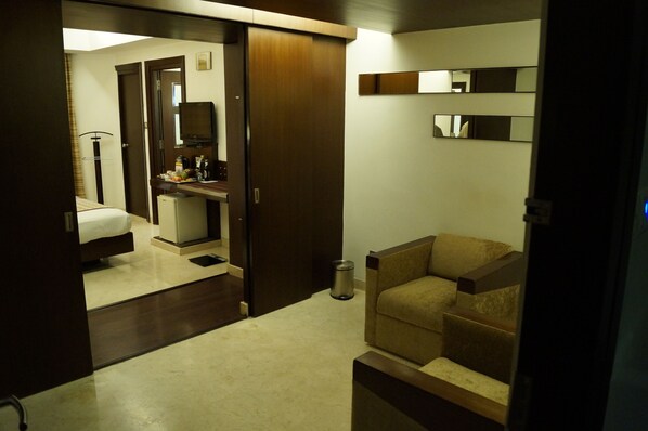 A hotel room with a bed, a small desk, a chair, a mirror, and a trash can.