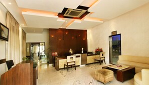 A modern hotel lobby with a reception desk, seating area, and a large mirror. - The President Hotel (Bengaluru)