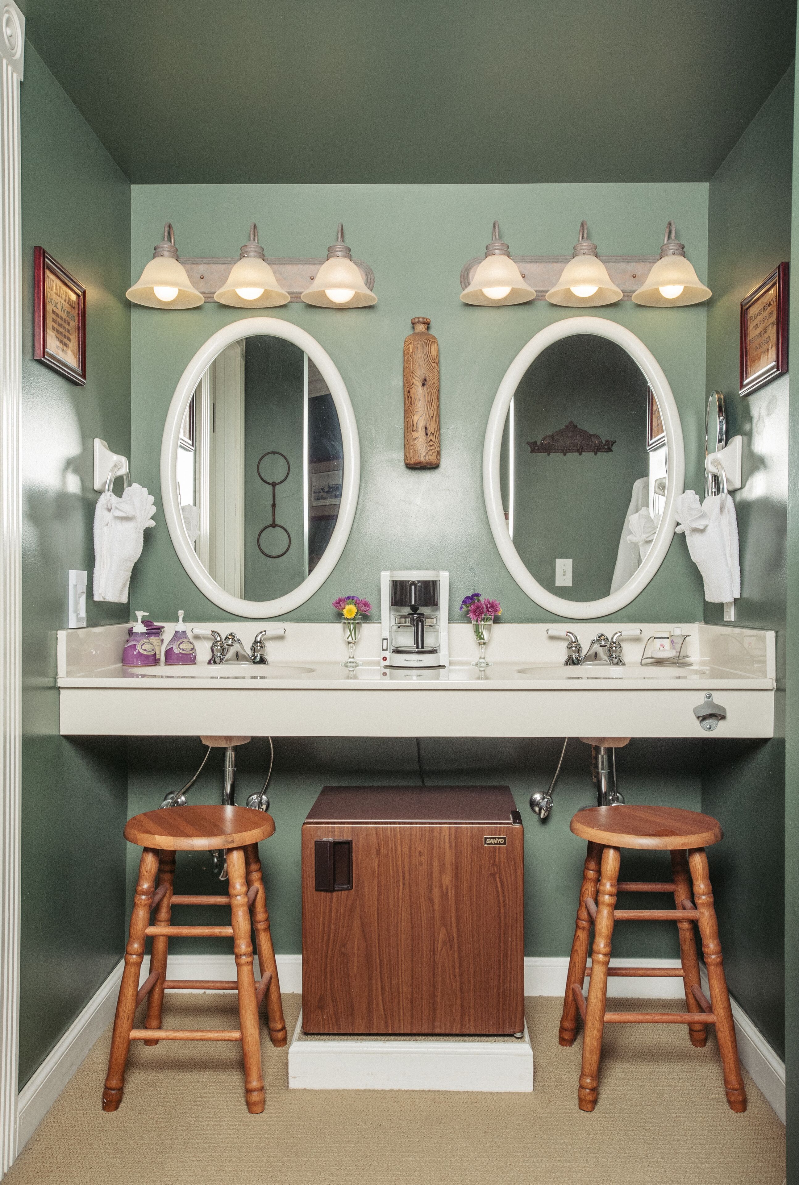 A bathroom with two sinks, two mirrors, and wooden stools.