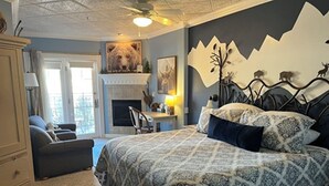 A bedroom with a large bed, a fireplace, a desk, and a chair. - Old Town GuestHouse B&B (Colorado Springs)