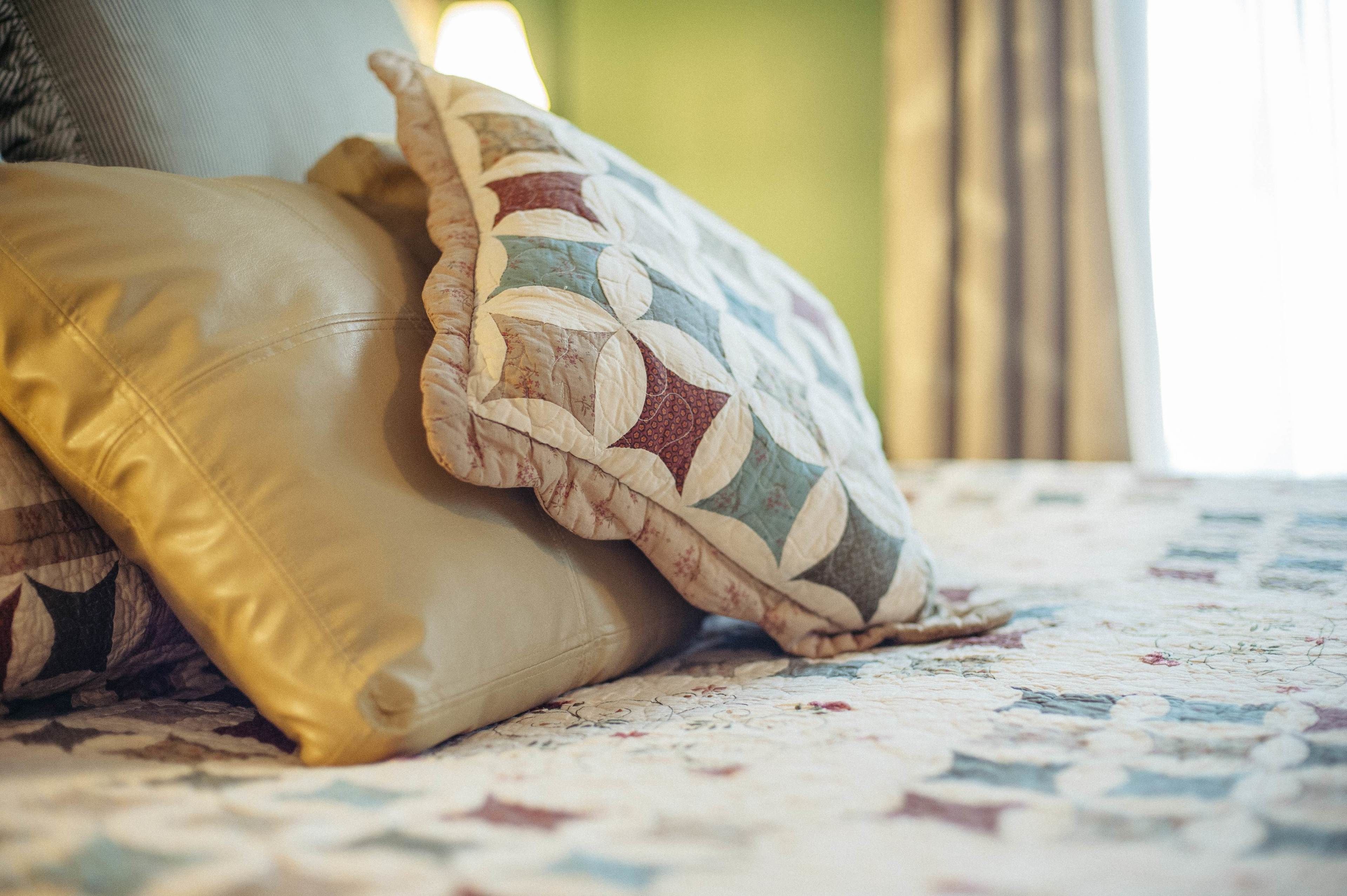 A bed with a quilted bedspread and two pillows.