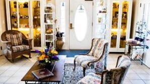 A spacious living room with a large arched doorway, two armchairs, a coffee table, and a bookshelf. - Old Town GuestHouse B&B (Colorado Springs)