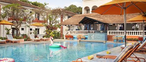 Una piscina con sillones de descanso, sombrillas y un flotador con forma de flamenco.