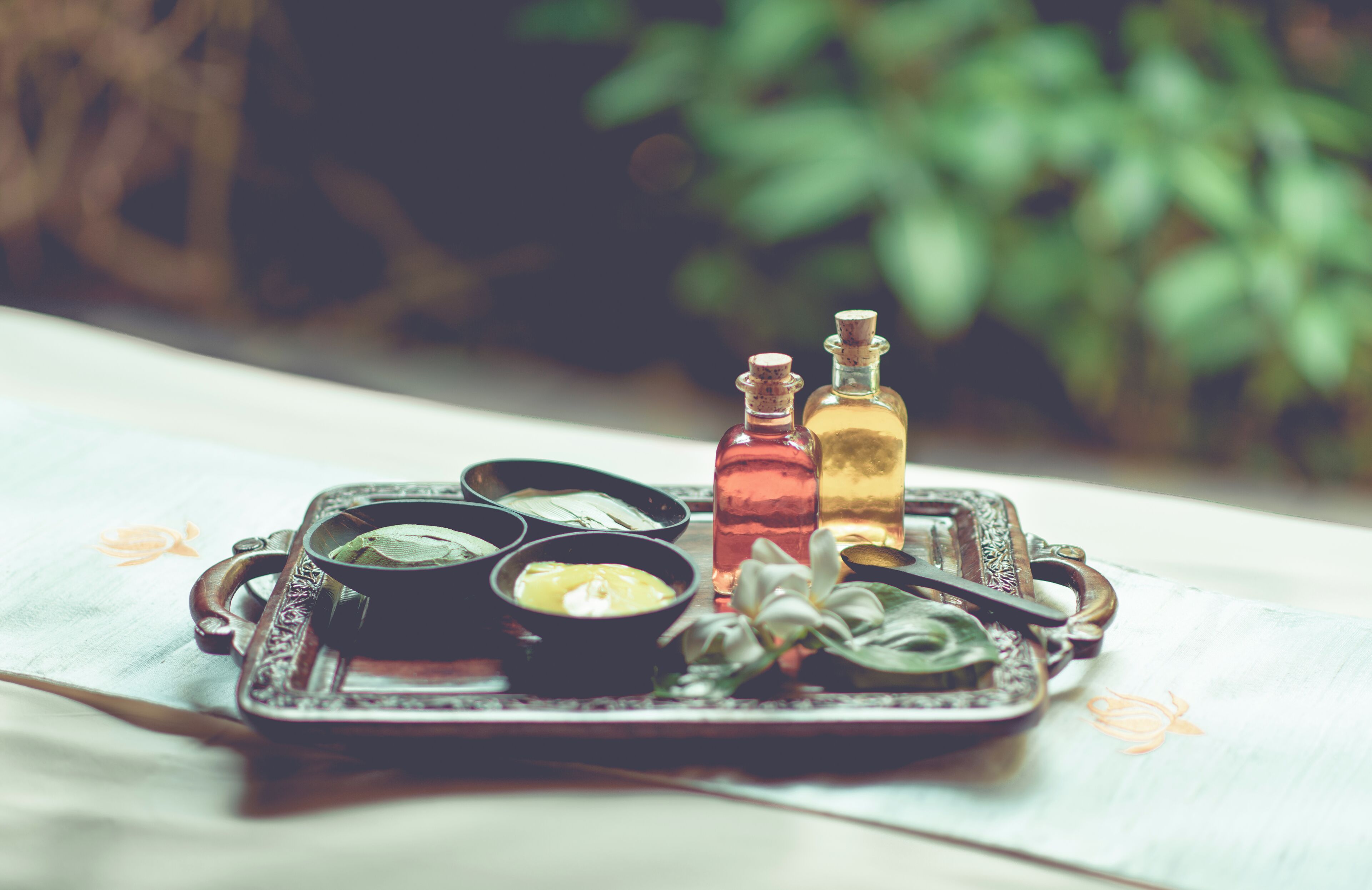 Una bandeja con diversos condimentos y dos botellas sobre una mesa con estampado floral.