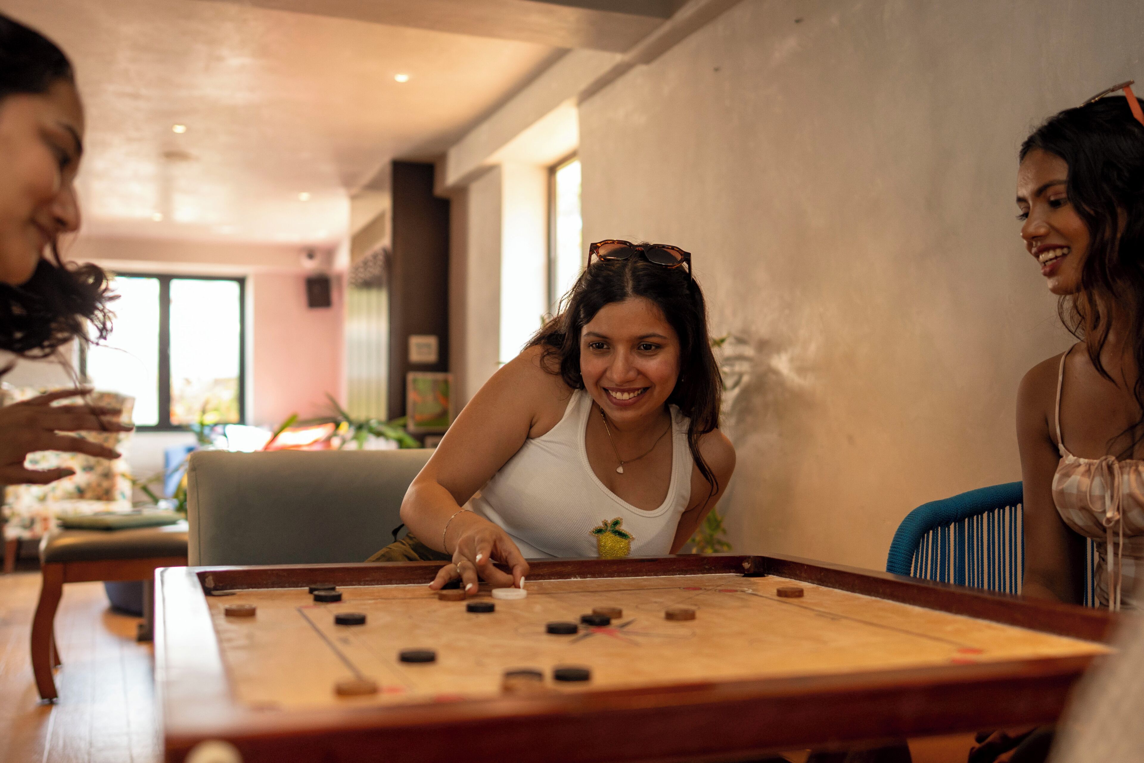 En grupp människor som spelar ett brädspel vid ett bord i ett rum med modern inredning.