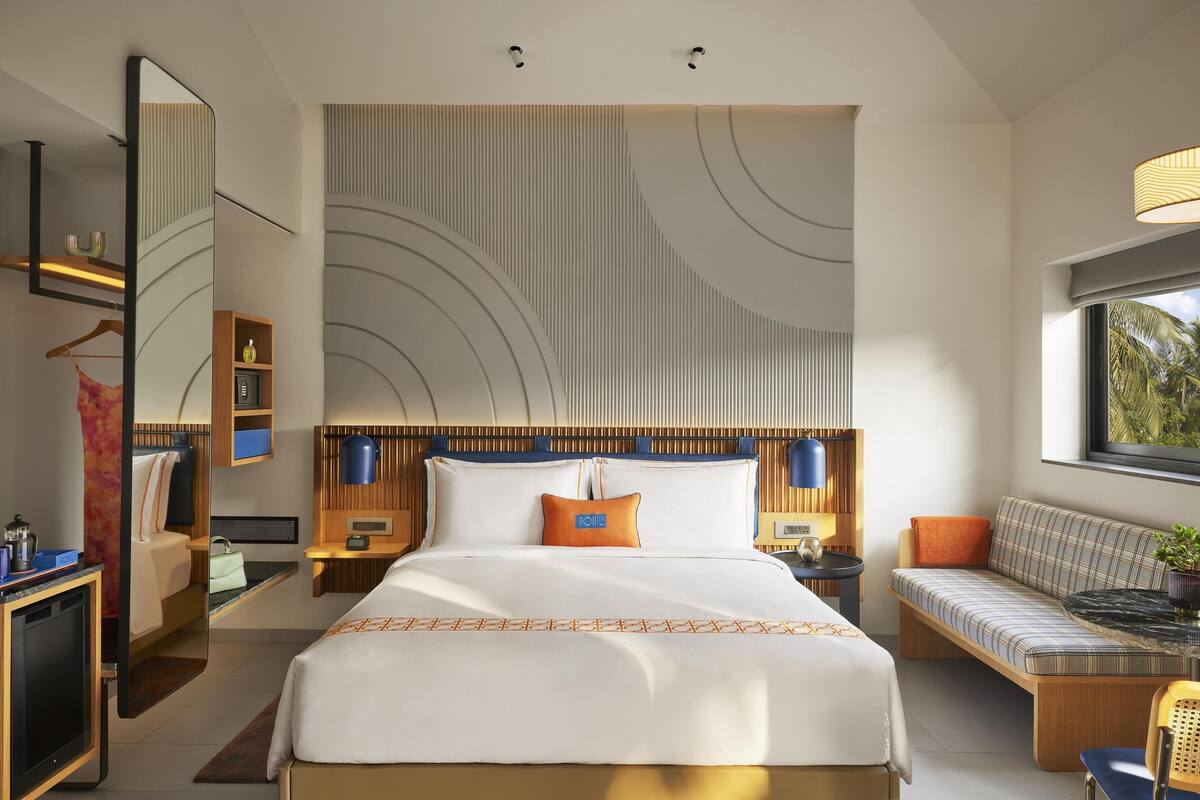 Une chambre d’hôtel moderne avec un grand lit, un canapé, un bureau et un miroir.