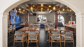 A restaurant with a central seating area, a bar, and a view of the outdoors. - Ronil Goa, JdV by Hyatt (Calangute)