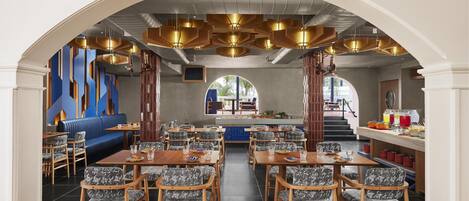 Un restaurante con un área central de mesas, una barra y vistas al exterior.