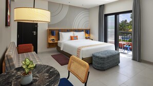 Une chambre d’hôtel moderne dotée d’un grand lit, d’un canapé, d’une table à manger et d’un balcon avec vue.