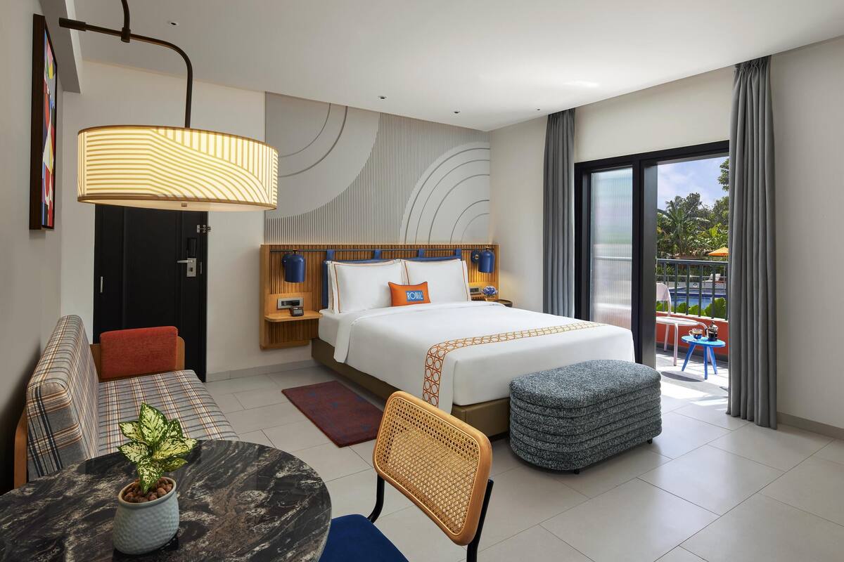 Une chambre d’hôtel moderne dotée d’un grand lit, d’un canapé, d’une table à manger et d’un balcon avec vue.