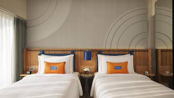 A hotel room with two beds, a wooden headboard, a mirror, and a wall with a circular design.