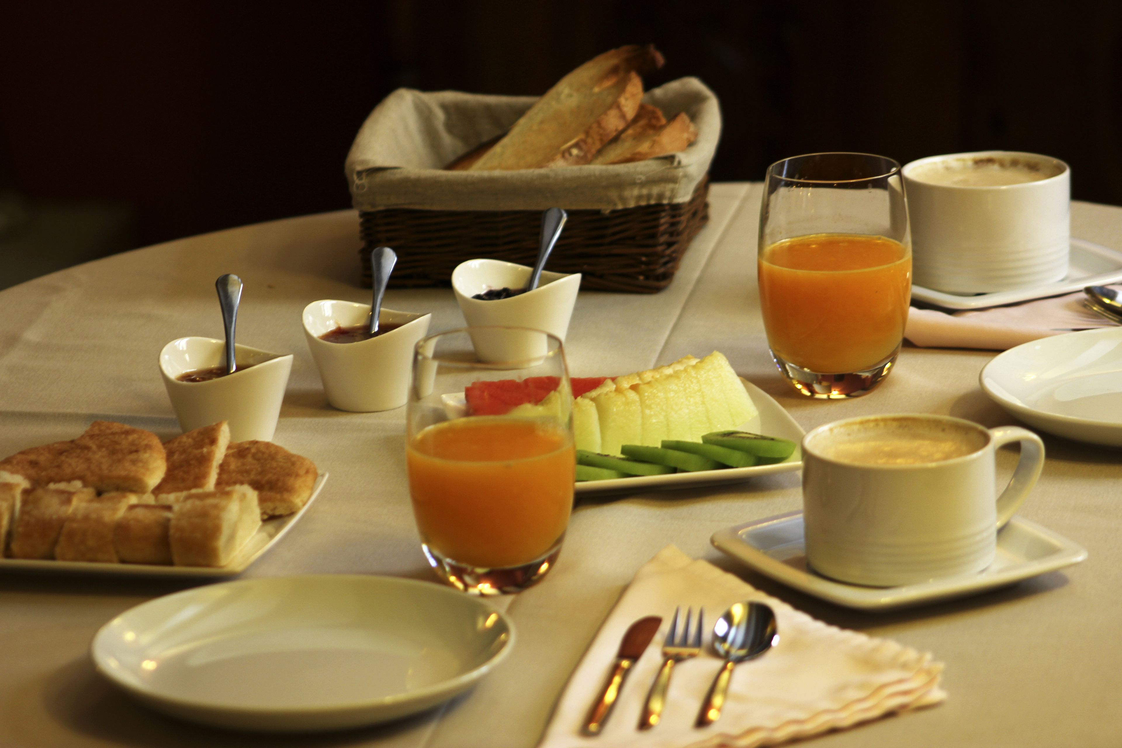 A breakfast setting with bread, fruit, and coffee on a table.