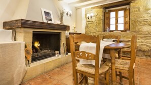 Una habitación acogedora con chimenea, paredes de piedra, muebles de madera y piso de baldosas.