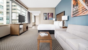 A hotel room with a large window, a bed, a sofa, a desk, and a TV. - La Quinta Inn & Suites by Wyndham Chicago Downtown (Chicago)