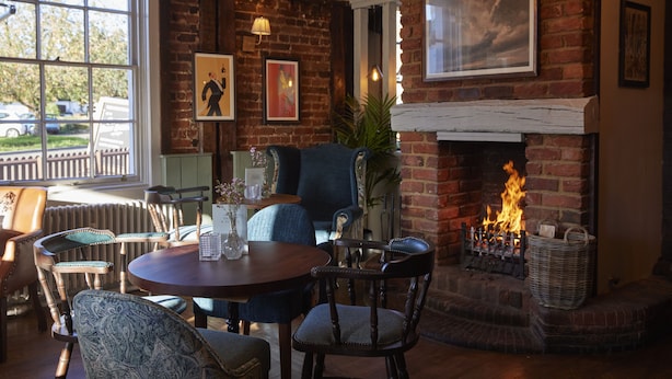 A cozy room with a brick fireplace, comfortable seating, and a view of the outside.